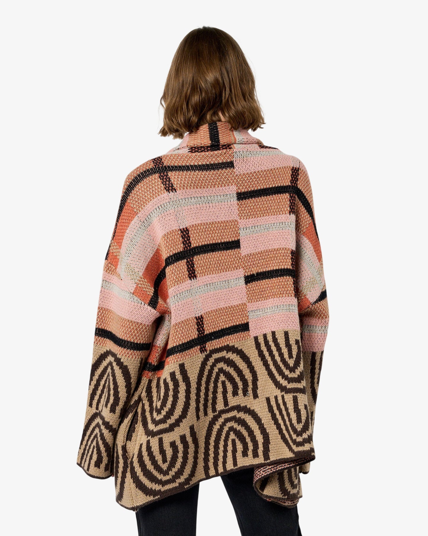 Person wearing a patterned sweater and black pants on a white background