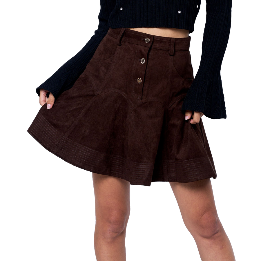 Woman wearing a black top with white polka dots and a brown skirt on a white background