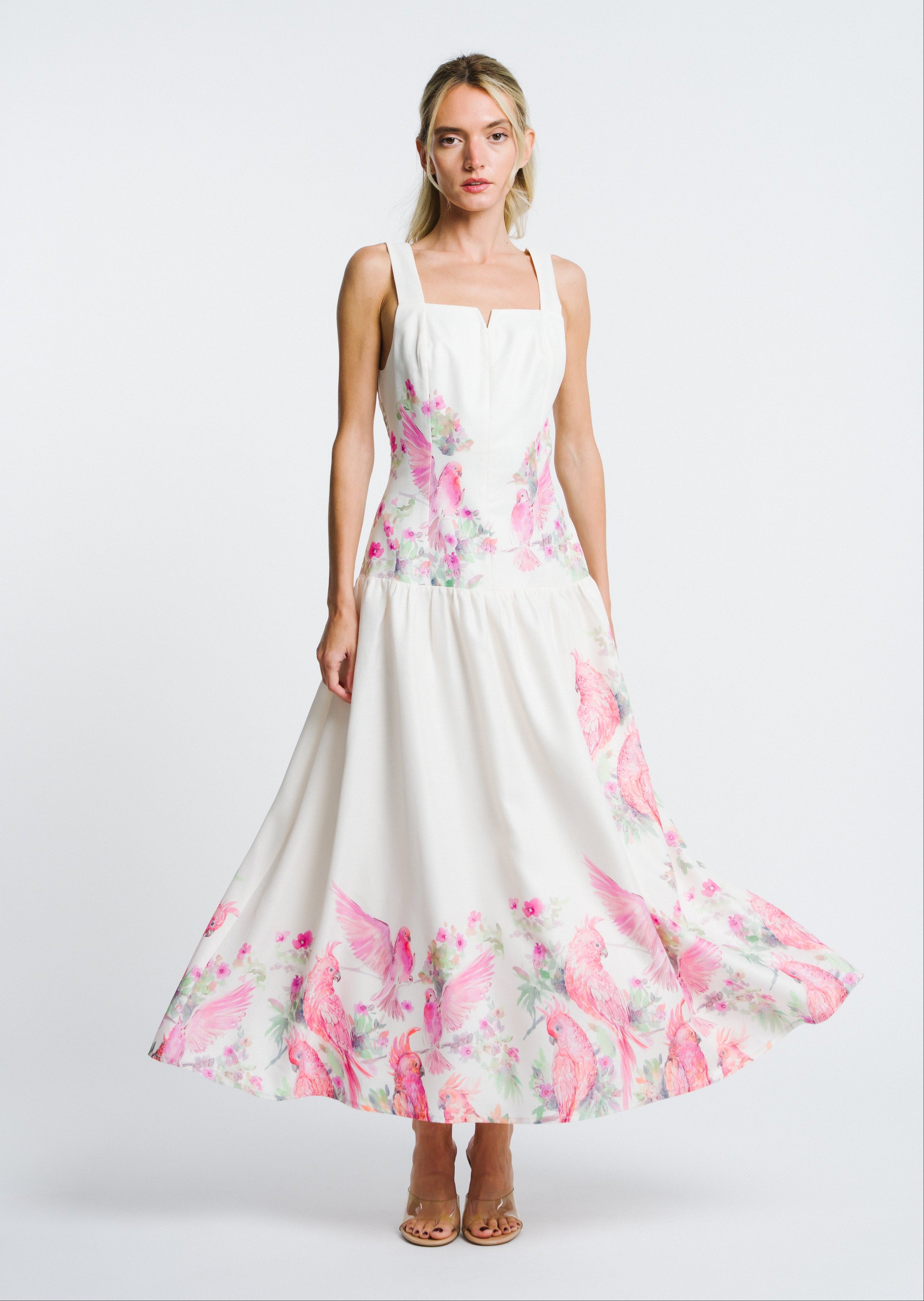 Woman wearing a white dress with pink floral patterns on a white background