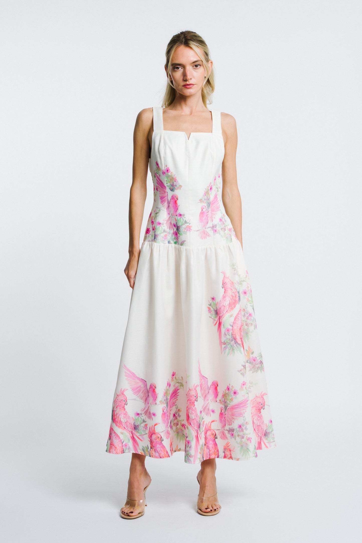 Woman wearing a white dress with pink floral pattern on a white background