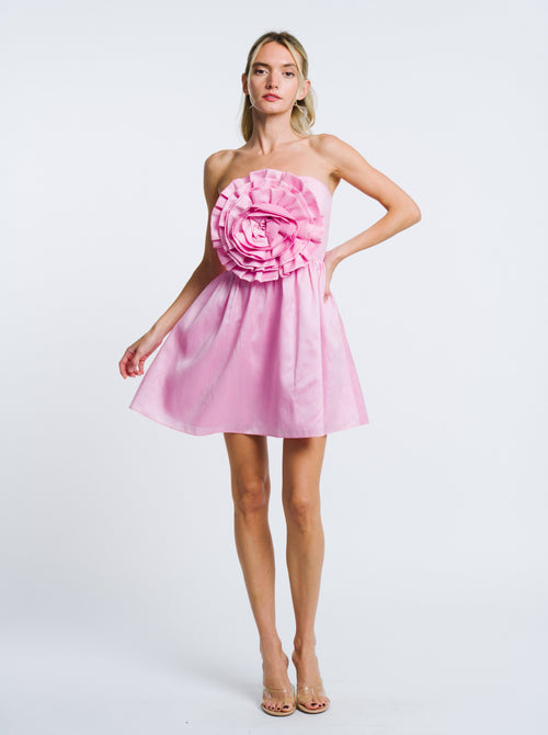 Load image 1 in gallery view. Woman wearing a pink strapless dress with a large floral embellishment on a white background