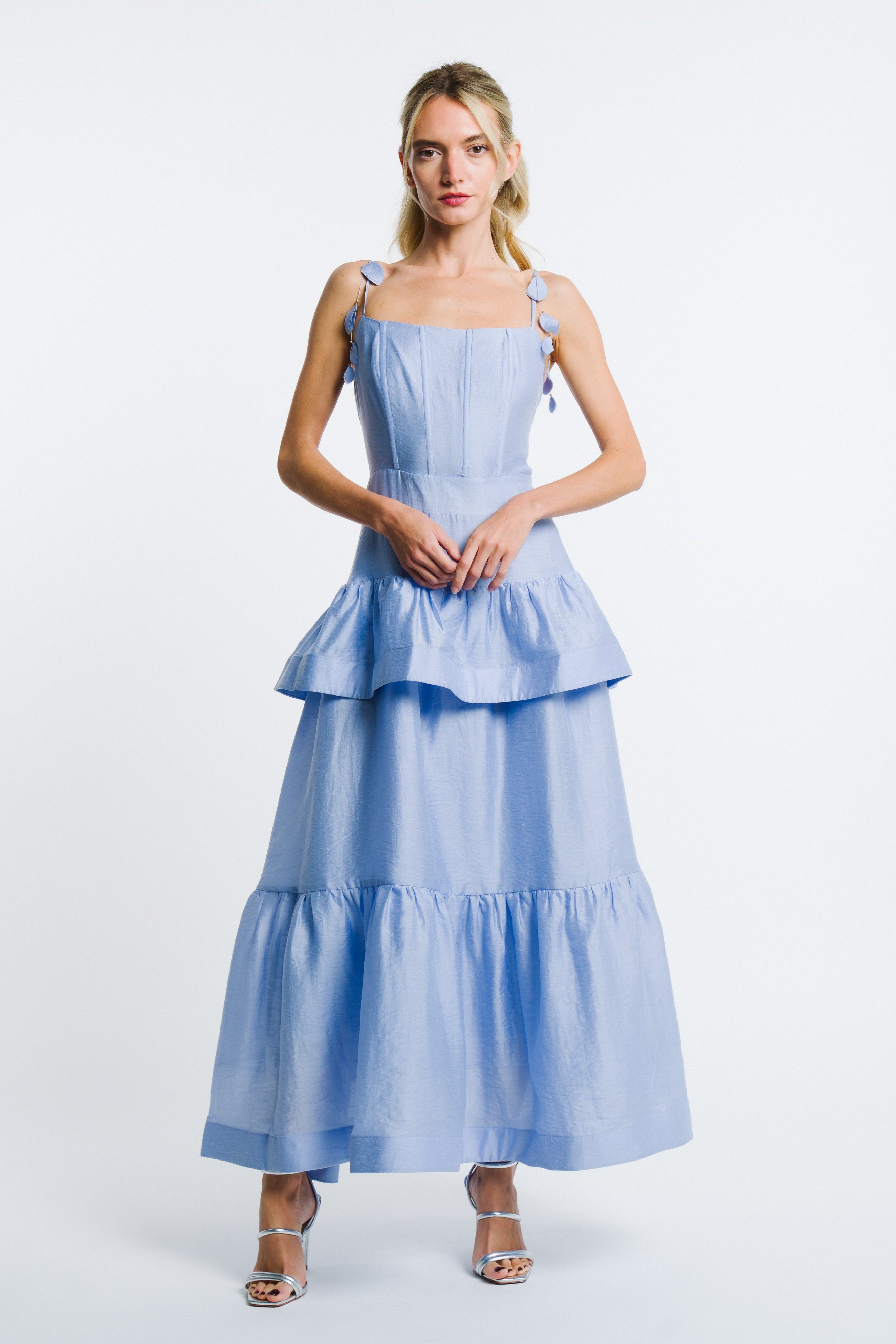 Woman wearing a light blue dress with ruffled layers on a white background