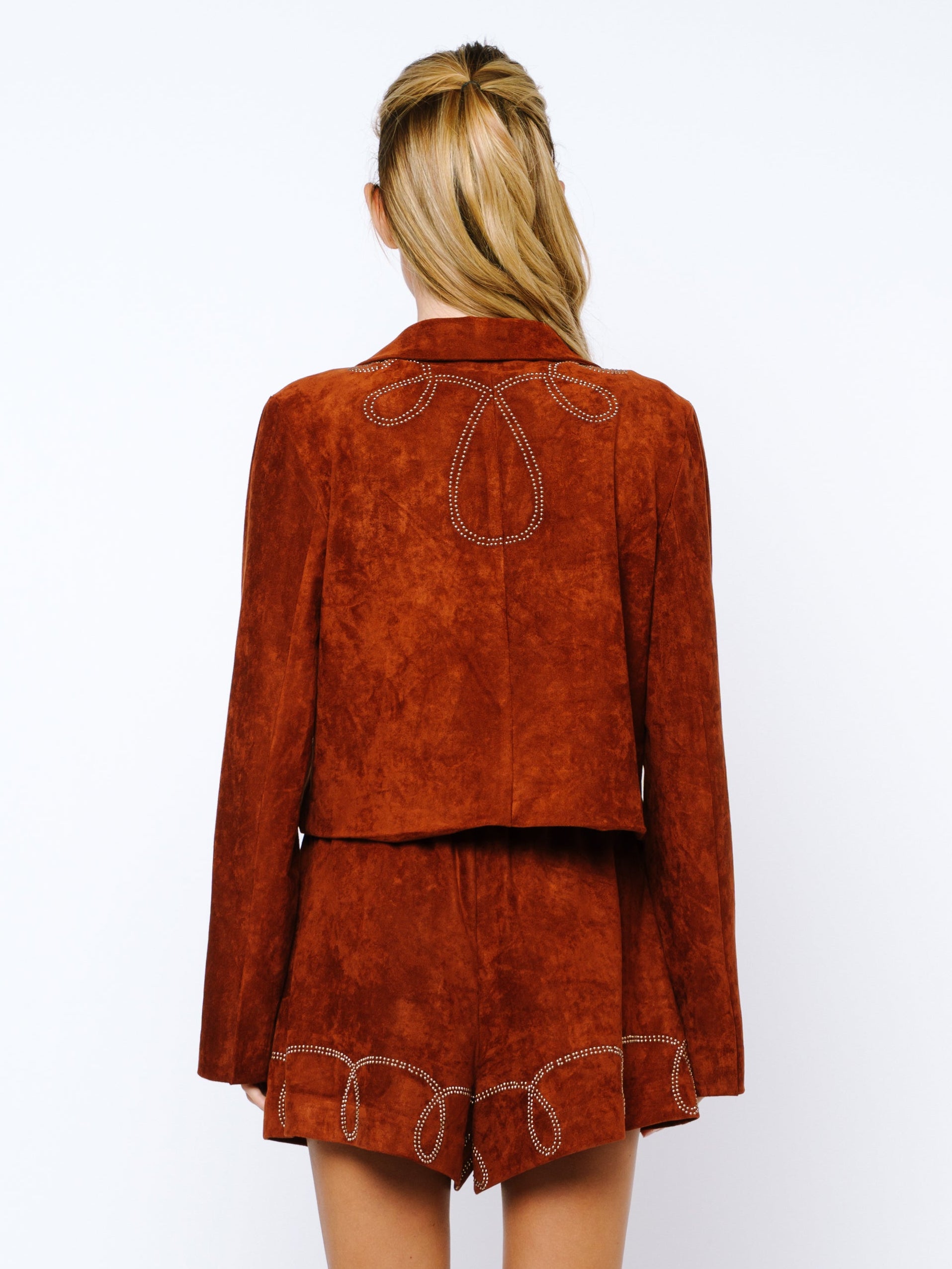 Person wearing a brown suede jacket and shorts set on a white background