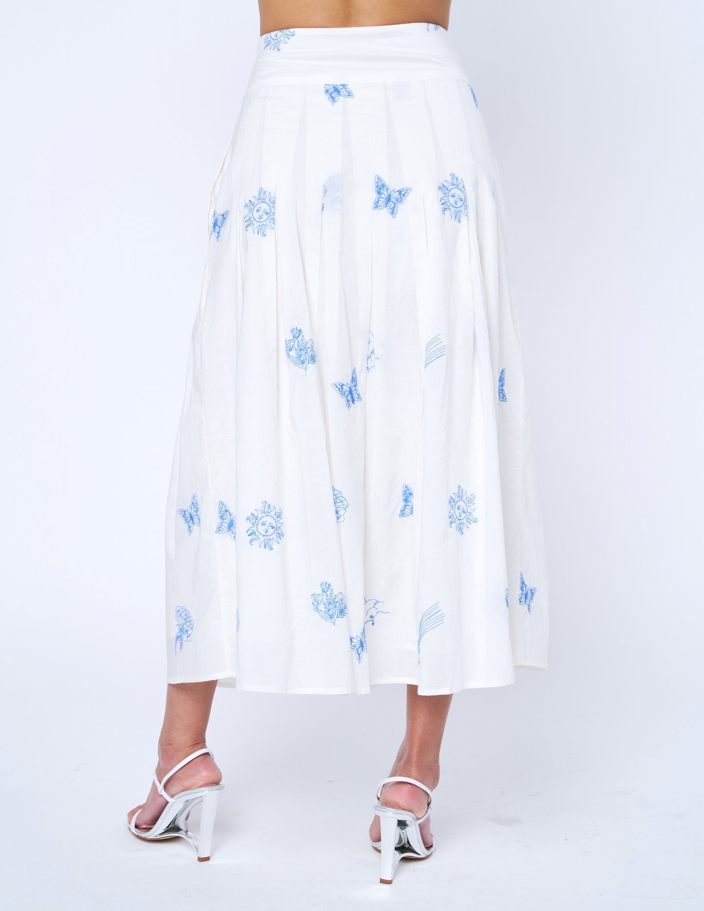 White skirt with blue floral patterns worn by a person on a white background