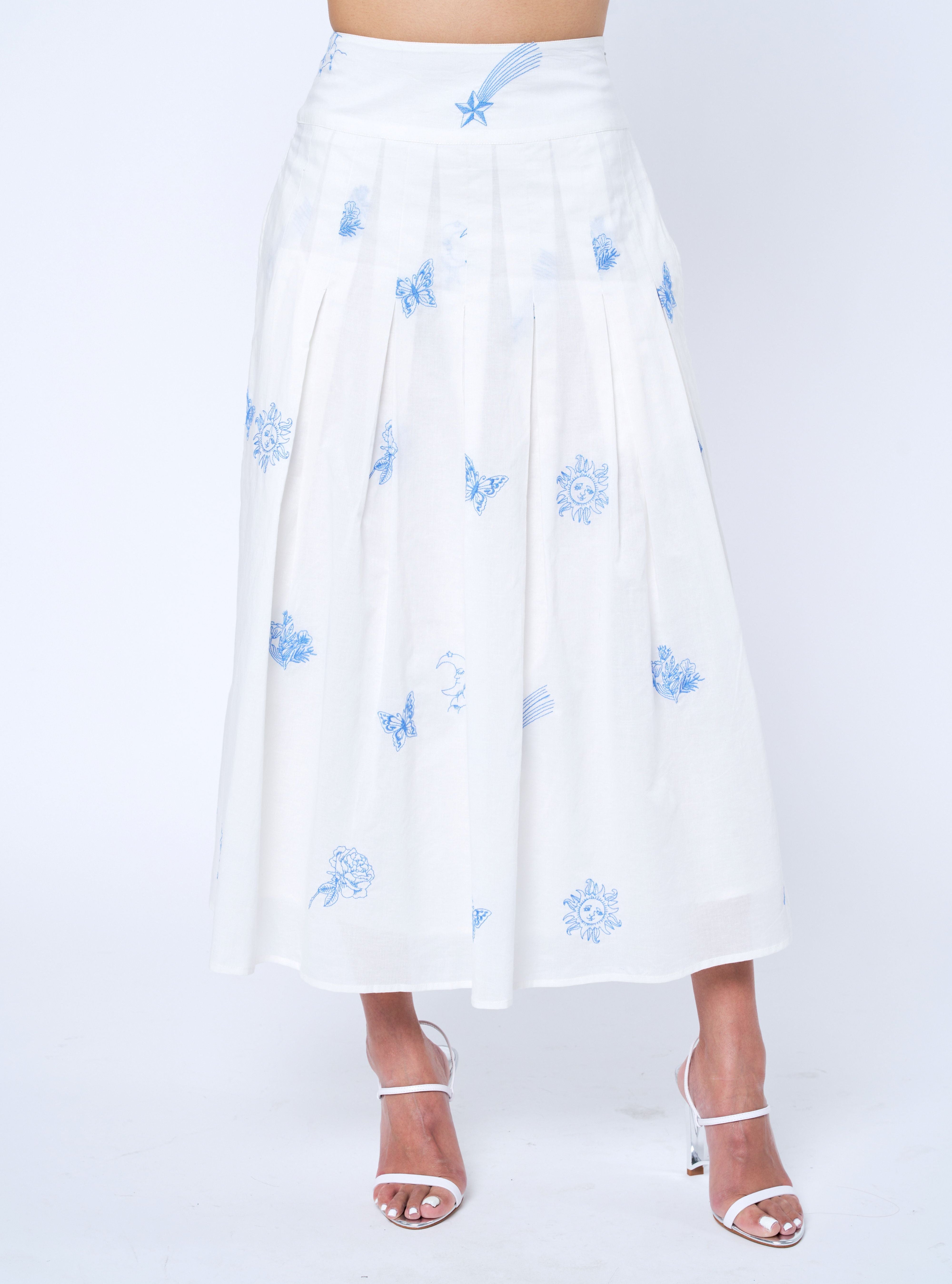 White skirt with blue floral patterns worn by a person on a white background