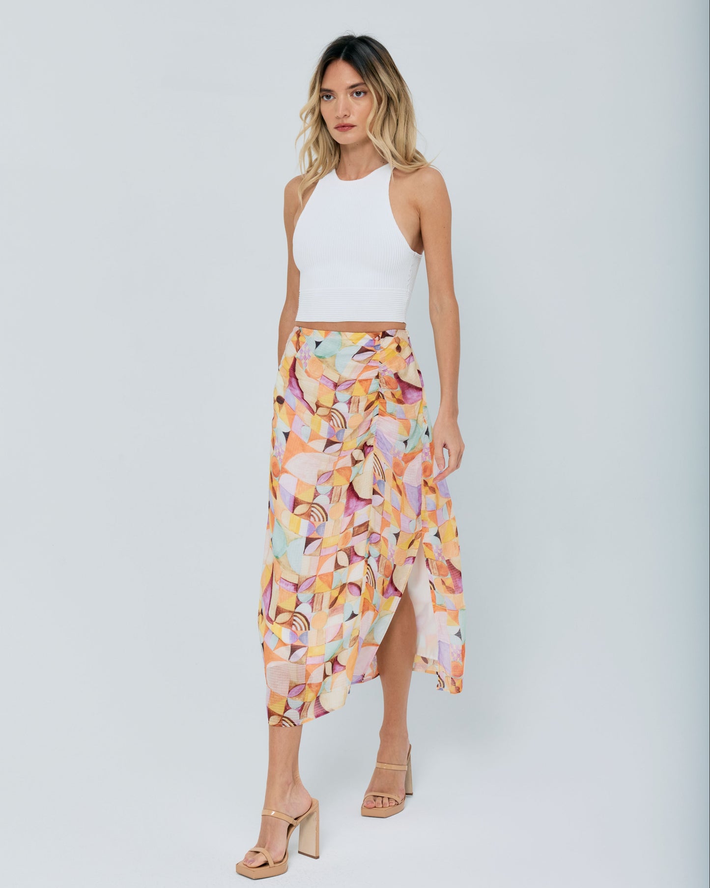 Woman wearing a white top and colorful skirt on a light gray background
