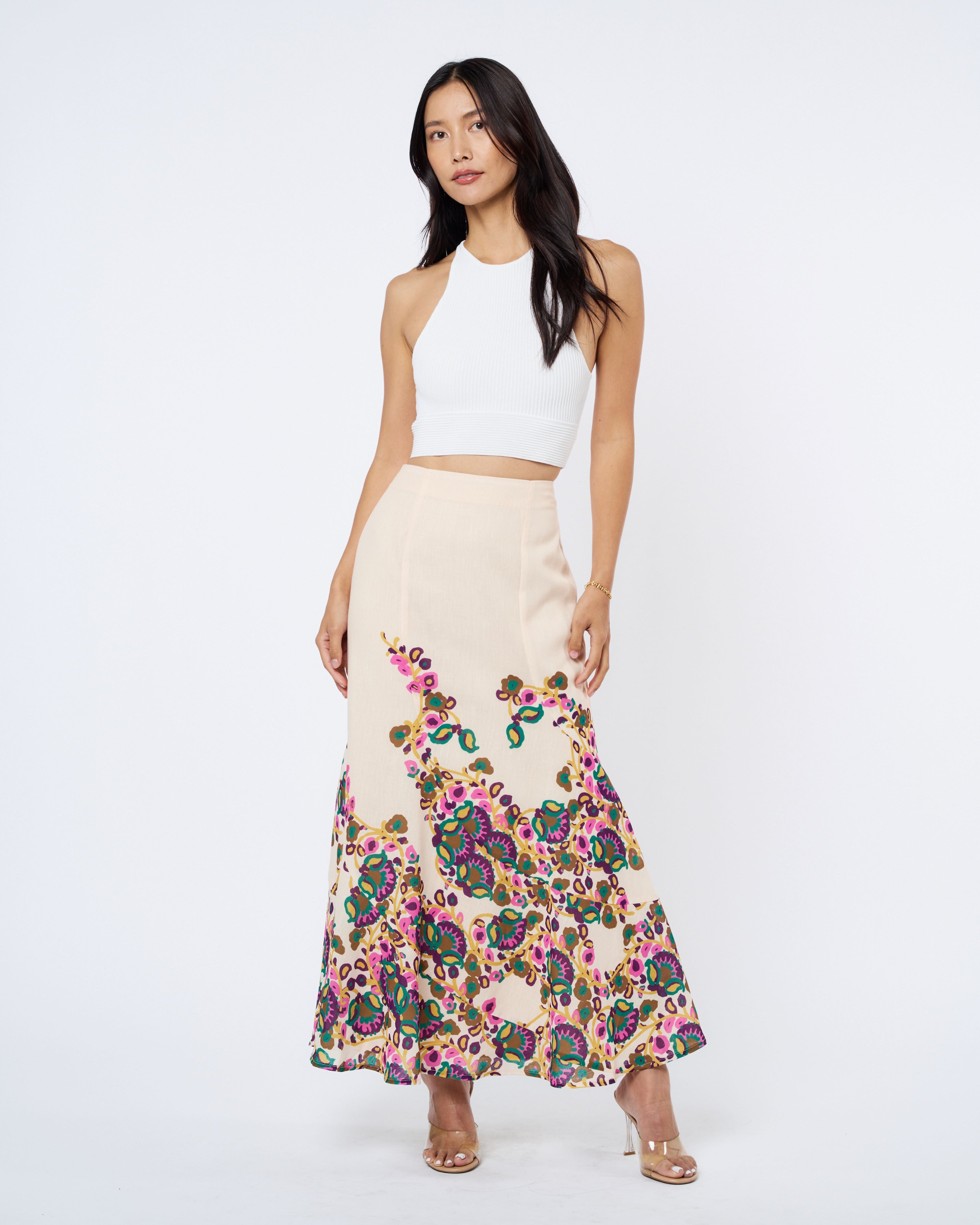 Woman wearing a white top and floral skirt on a white background