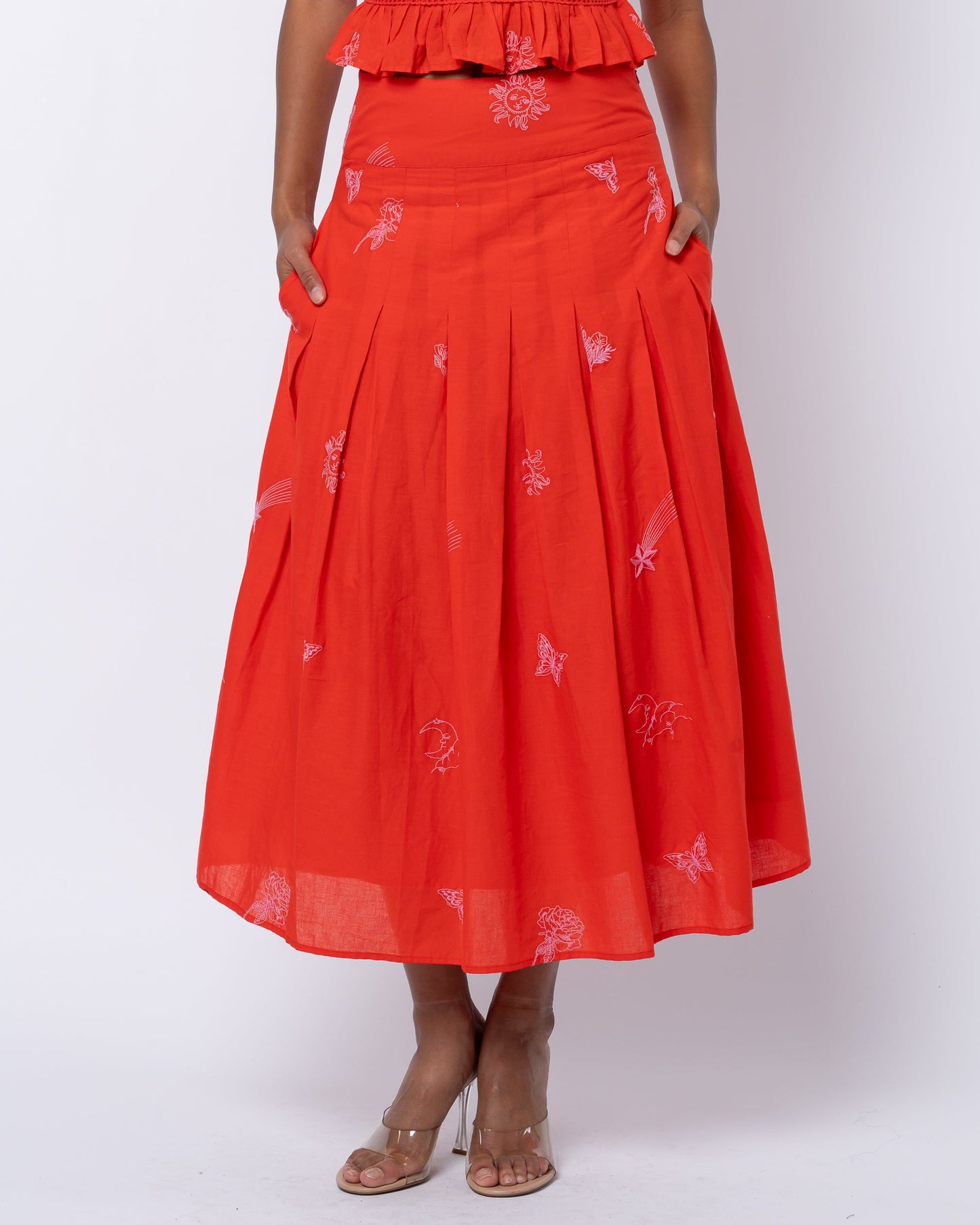 Woman wearing a red dress with floral patterns on a white background