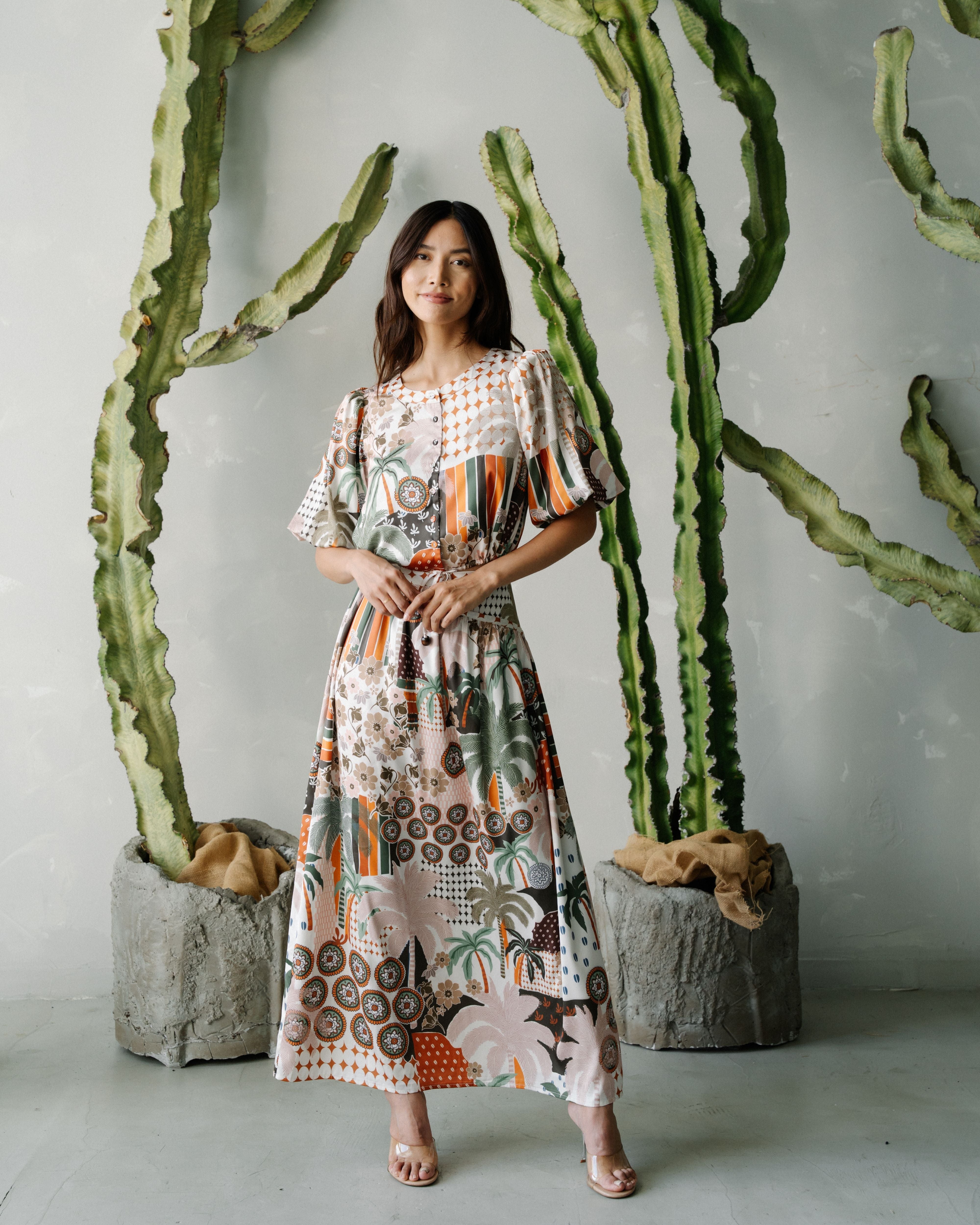 Woman in a patterned dress standing in front of cacti