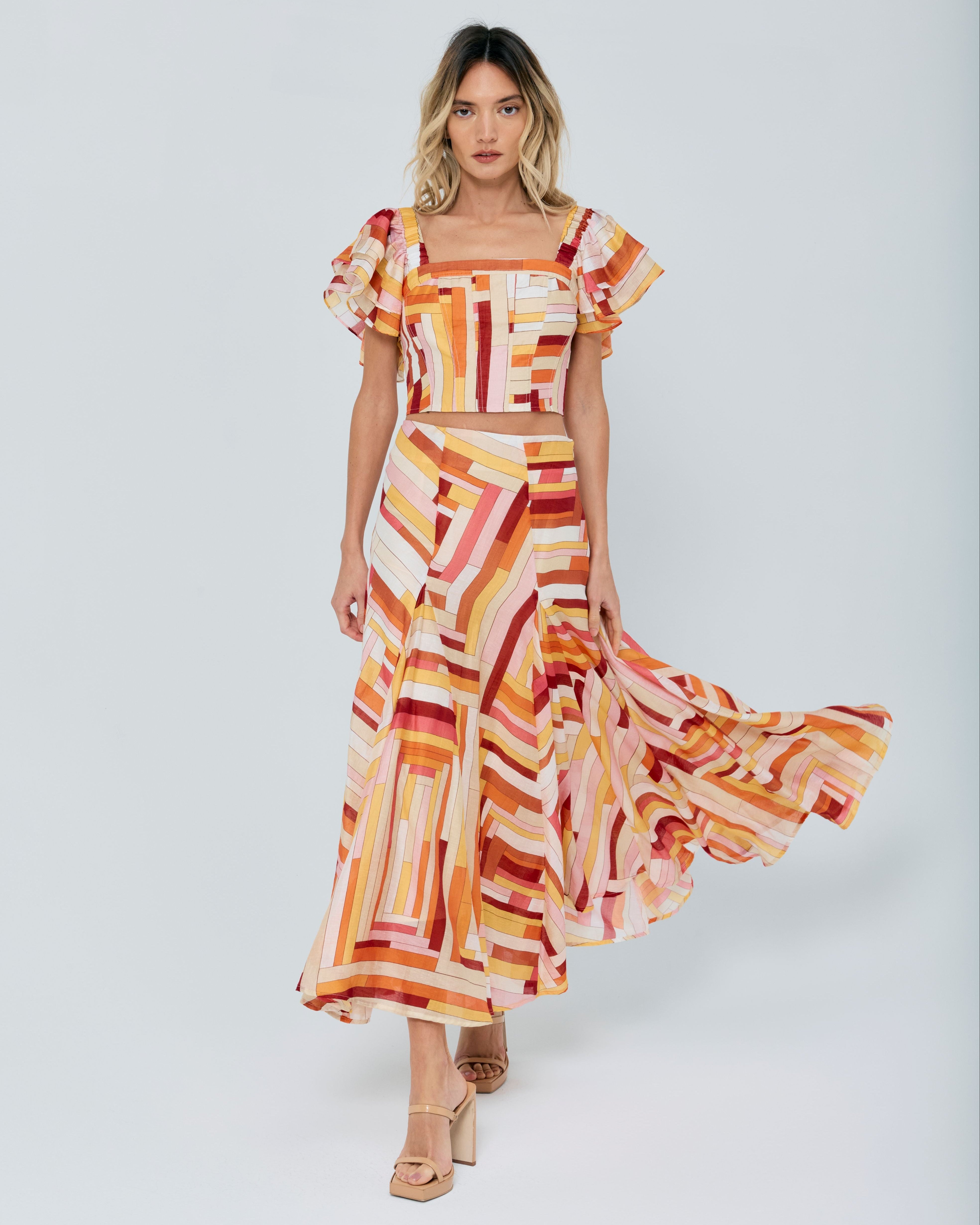 Woman wearing a colorful dress with ruffled sleeves on a white background