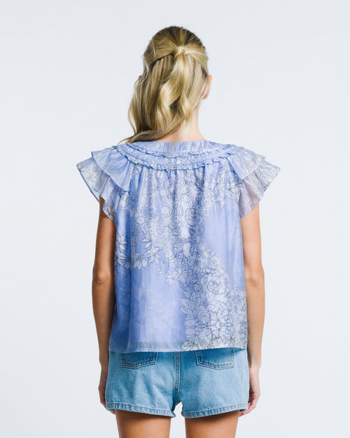 Load image 1 in gallery view. Woman wearing a light blue embroidered top and denim shorts on a white background