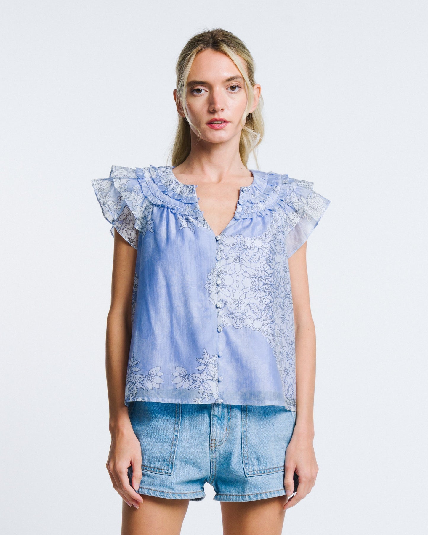 Woman wearing a light blue denim top with lace details and matching shorts on a white background