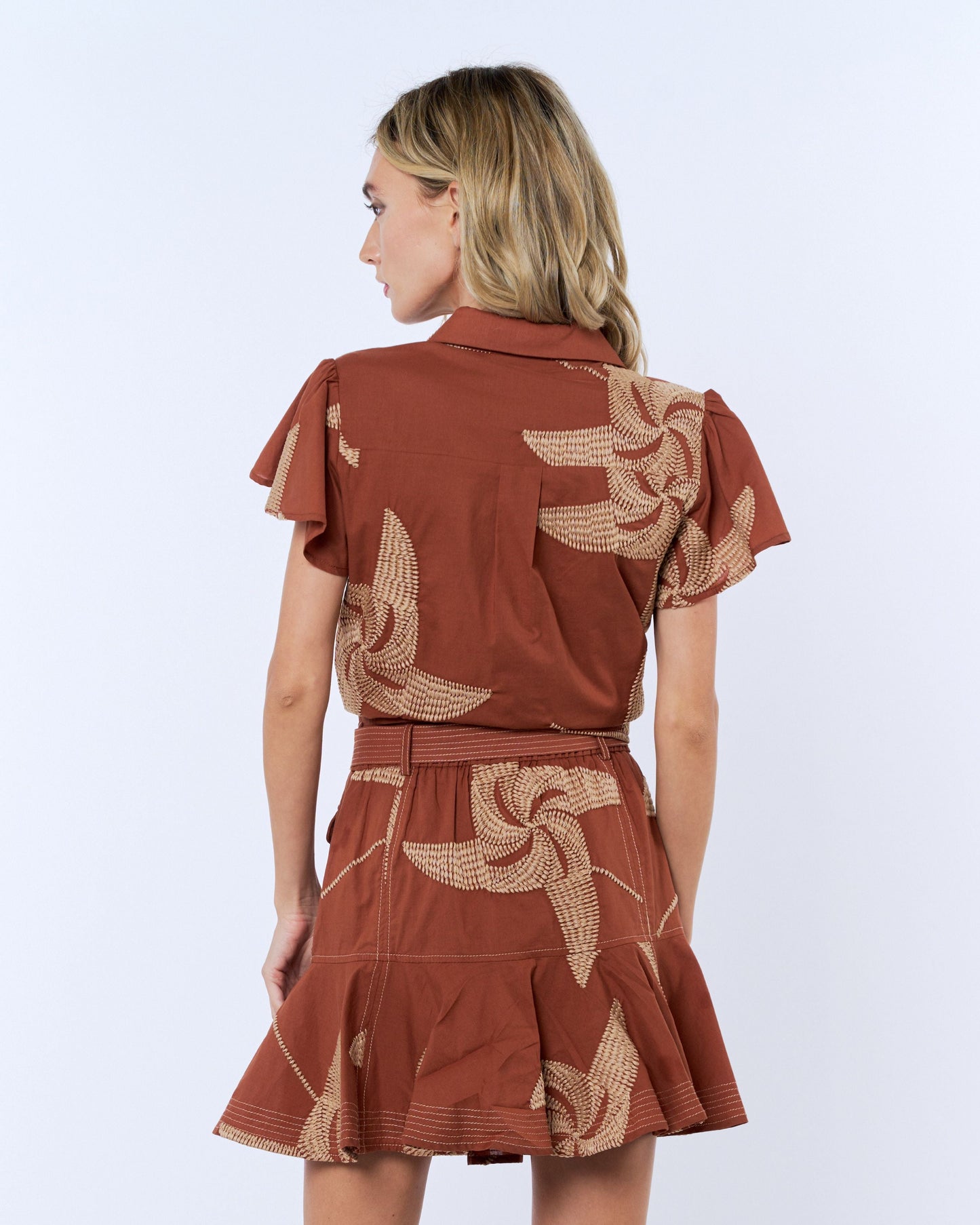 Woman wearing a rust-colored dress with floral patterns on a white background