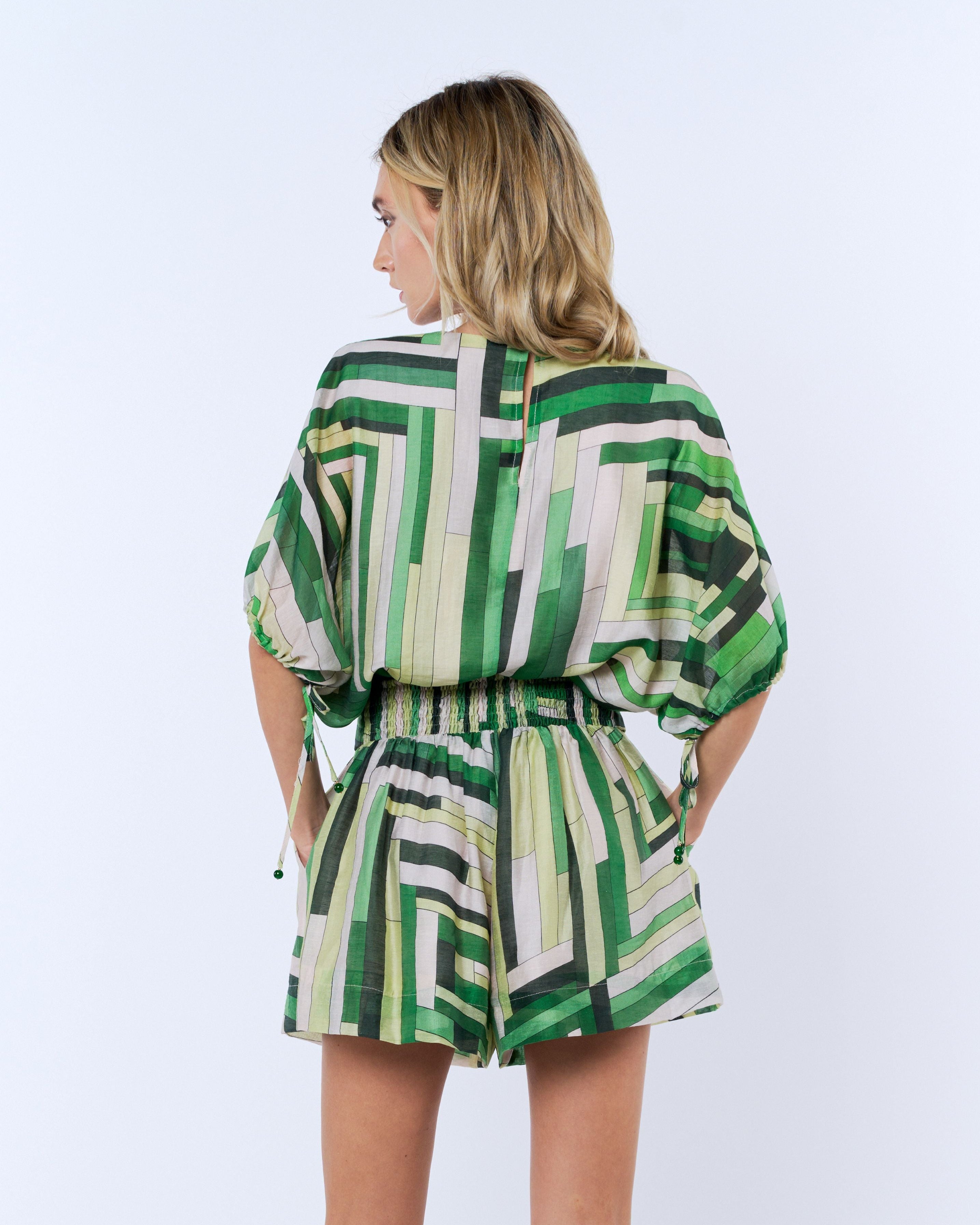 Woman wearing a green and white patterned outfit on a white background