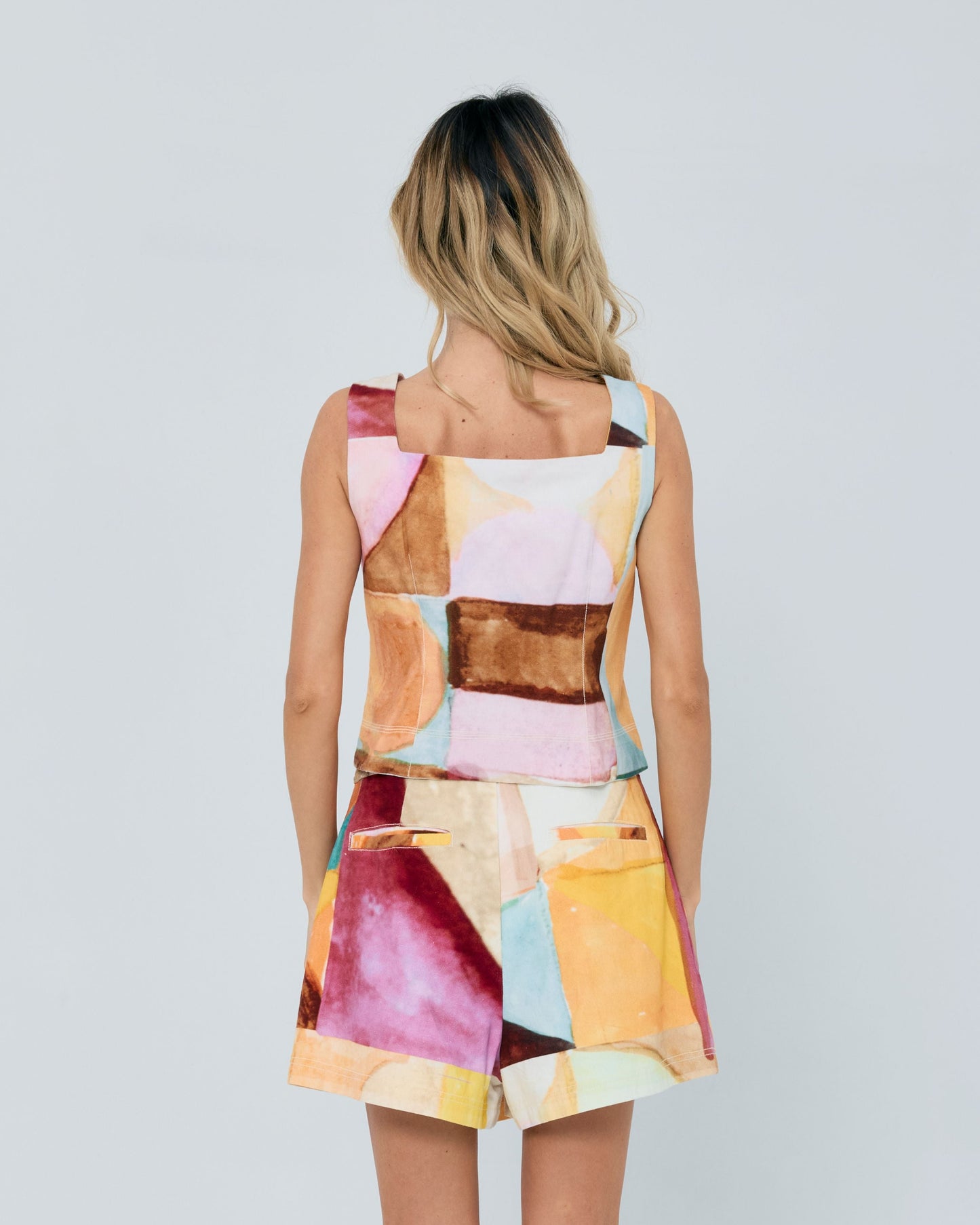 Woman wearing a colorful abstract pattern dress on a plain background