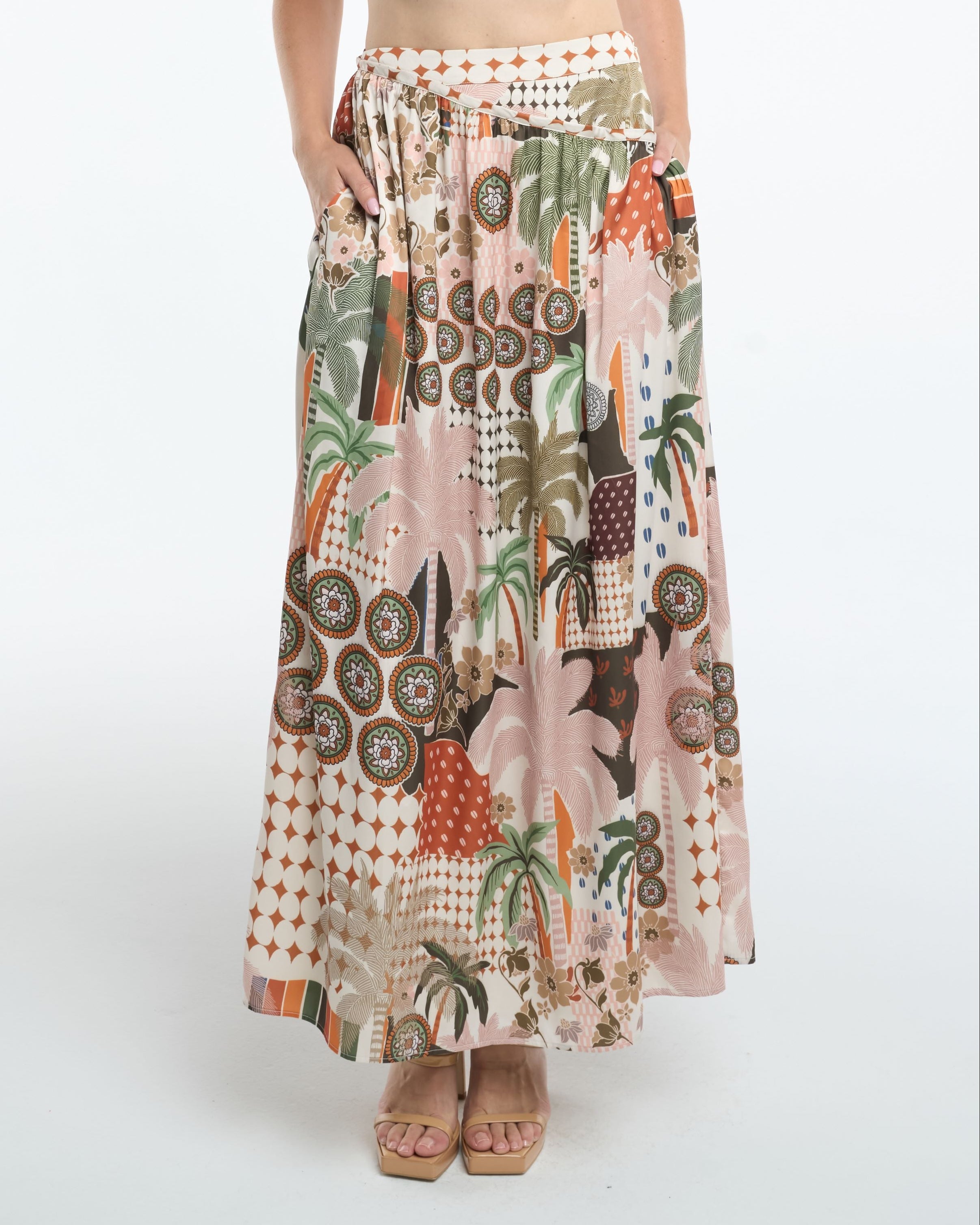 Woman wearing a patterned skirt and beige top on a white background